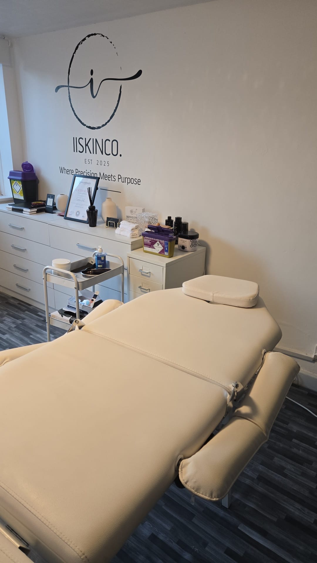 Treatment bed in front of the IISKINCO logo wall